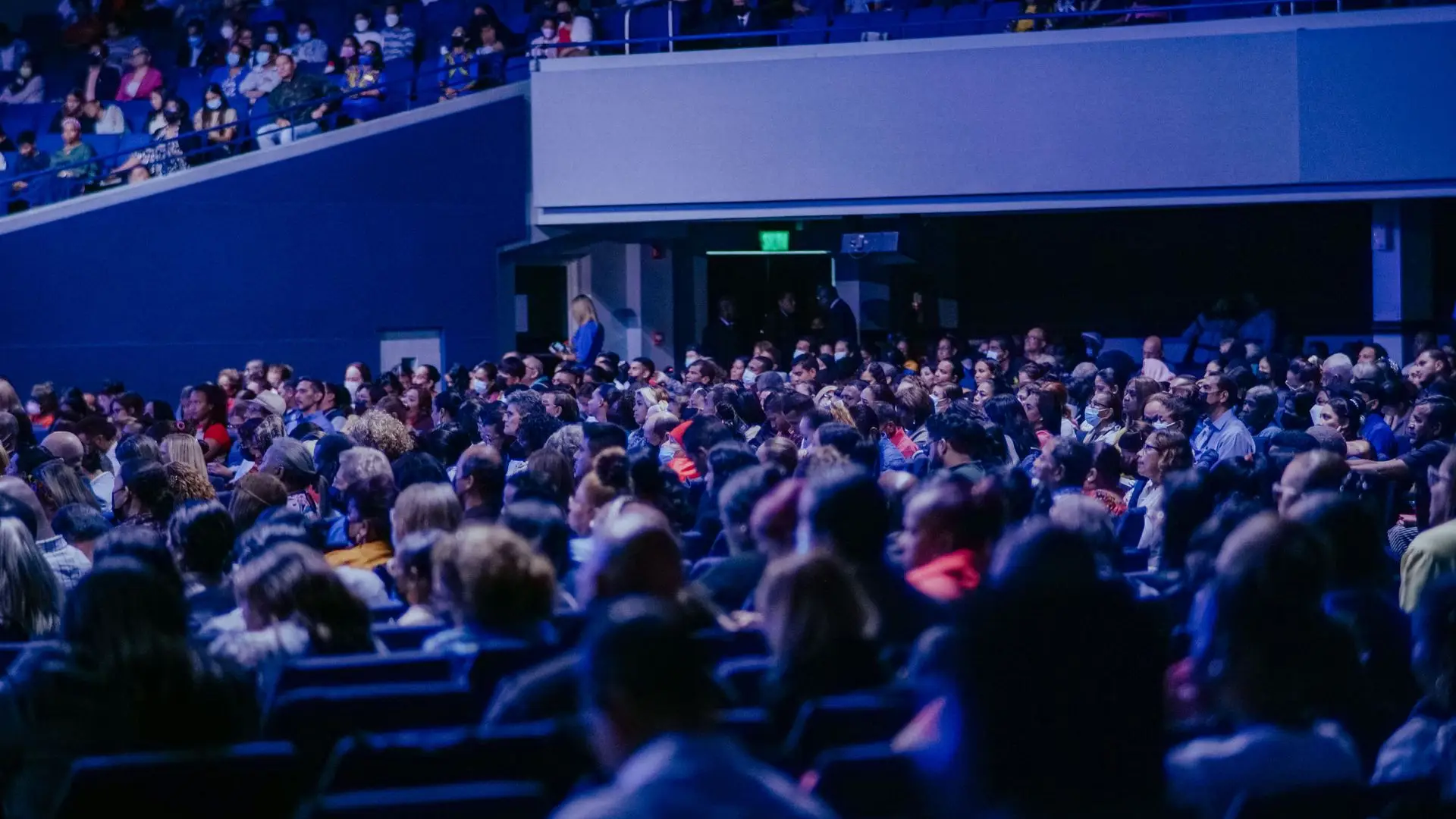 Kalabalık bir kongre salonunda sahneyi izleyen dinleyiciler